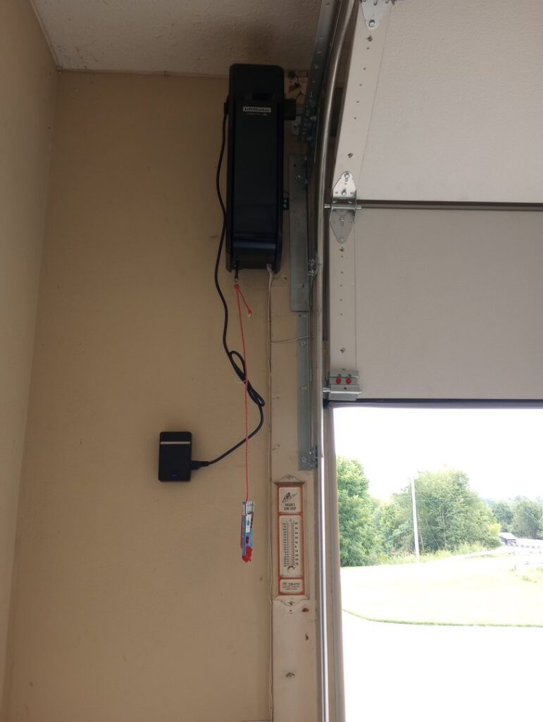 A side-mount garage door opener installed next to a white garage door by Precision Garage Door of Owensboro Evansville in Owensboro, KY.