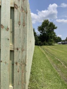 A side view of a newly installed treated wood privacy fence, showcasing quality by 985 Fence, LLC in Schriever, LA.
