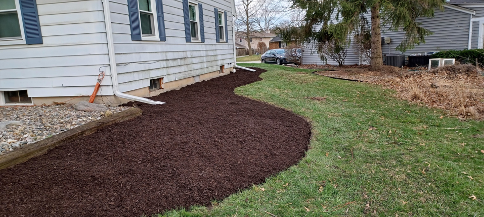 A newly mulched landscape bed along the side of a house by VKDYS Lawn Care in Fort Wayne, IN.