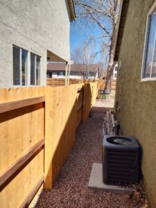 A newly installed wood fence and gate in a narrow side yard, providing access and security from Good Neighbor Fencing, LLC in Colorado Springs, CO.