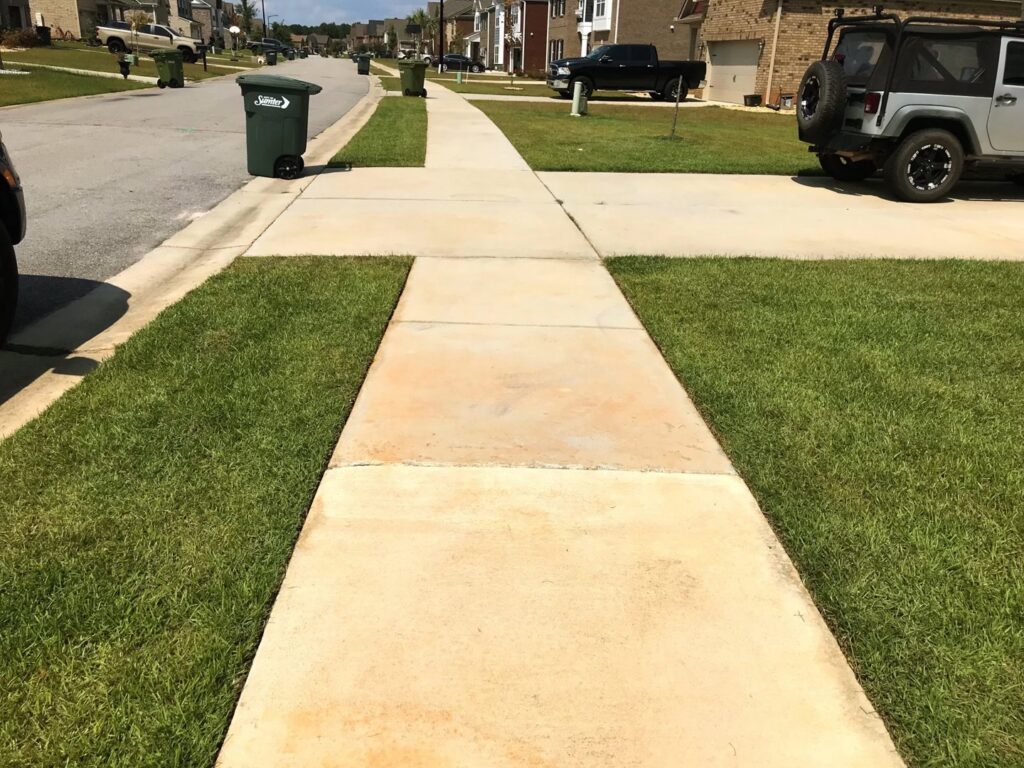 Neatly edged and mowed grass along a sidewalk and curb by Kirby's Lawn Care Service in Franklinton, LA.