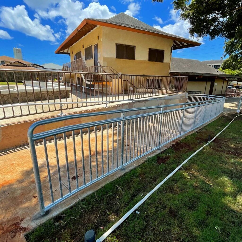A newly installed silver metal handrail along an accessibility ramp for a building by A&D Services in Kapolei, HI.