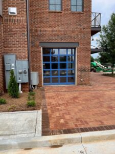 A single blue glass garage door installed on a brick commercial building by Precision Door Service of Huntsville, AL.