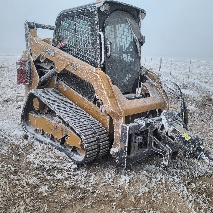 A skid steer loader with an auger attachment, used for fence post installation by Life Time Fence, Inc. in Cedar Rapids, IA.