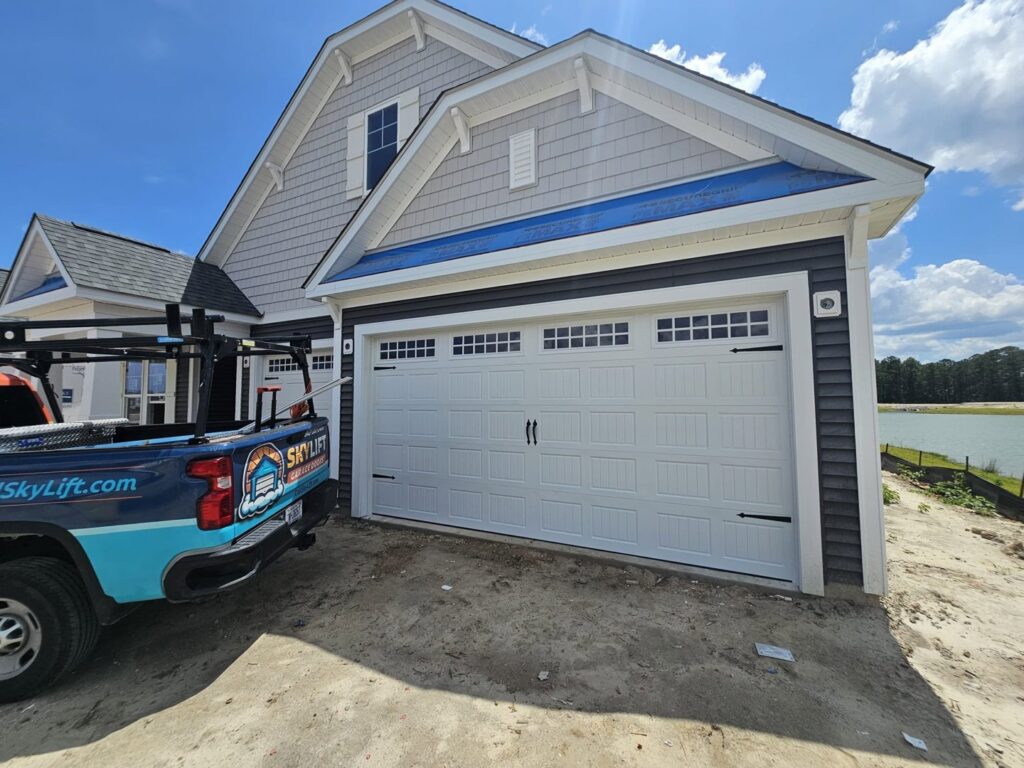 Skylift Garage Doors truck parked next to a newly installed white garage door on a house under construction in Knoxville, TN