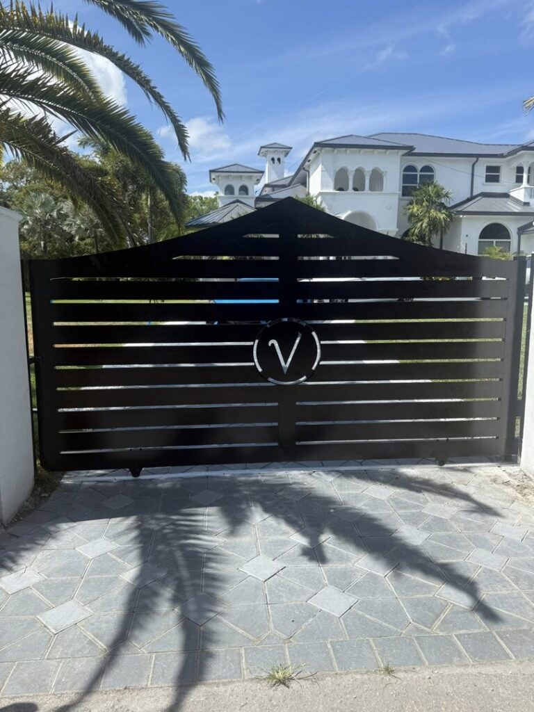 A sleek black horizontal slat gate with a custom 'V' emblem, installed by A Master Work Corp. in Hialeah, FL.