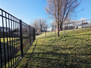 A long stretch of black metal fence installed on a sloped residential property by Green Acres Fence Co in Salina, KS.