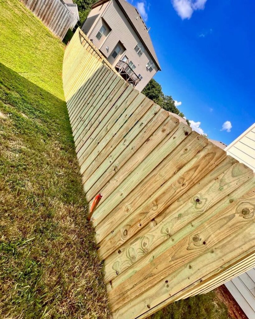 A wood privacy fence expertly installed on a steep slope by Hawk Fences LLC in Johns Creek, GA.