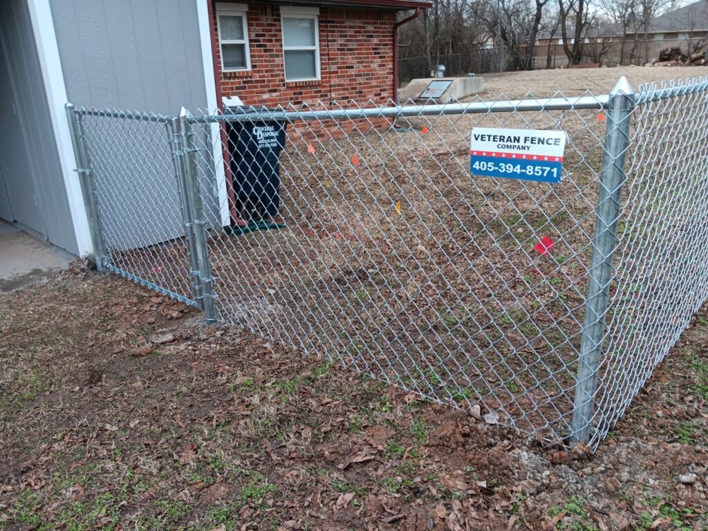 A small chain-link fence enclosure installed next to a building by Veteran Fence Company LLC in Shawnee, OK.