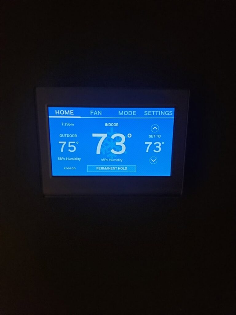 A smart thermostat display showing indoor and outdoor temperatures, installed by T. D'Albora Heating and Cooling in Erie, PA.