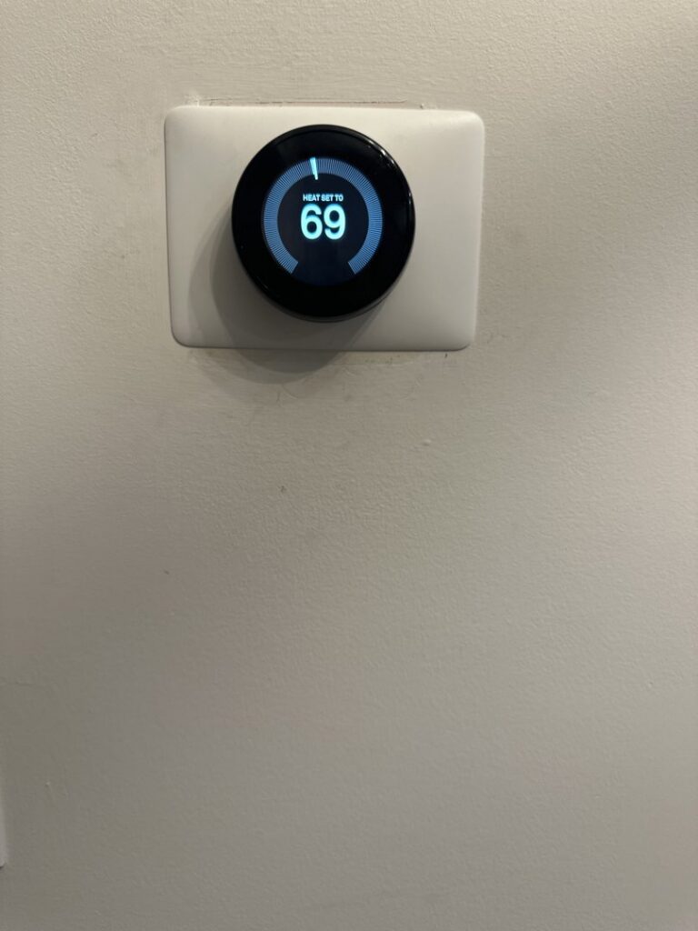 A smart thermostat displaying 'HEAT SET TO 69' on a wall, installed by On Call Plumbing, Heating & Air in Columbia, SC