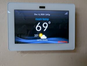 A smart thermostat displaying the room temperature and weather, installed and configured by Bloomington Heating & Air in Bloomington, MN.
