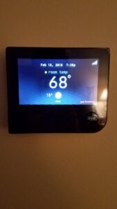 A modern smart thermostat installed on a wall by Kelly Heating & Electric, LLC in Eau Claire, WI.