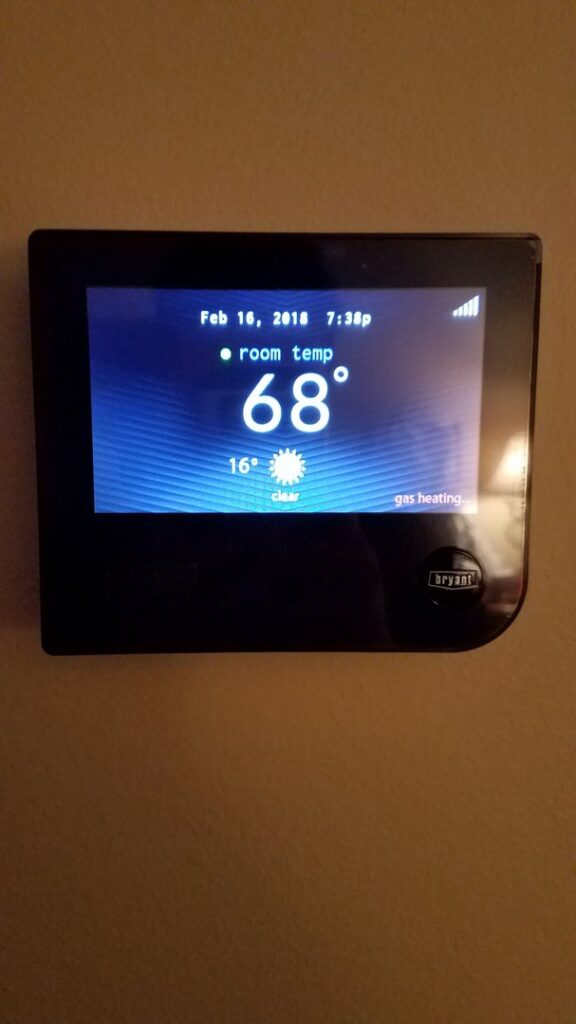 A modern smart thermostat installed on a wall by Kelly Heating & Electric, LLC in Eau Claire, WI.
