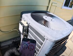 A smartphone displaying HVAC diagnostic readings next to an outdoor AC unit by RESTQ HVAC Repairs & Services in Rockville, MD.