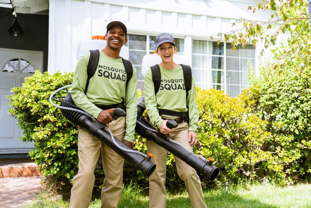 Two smiling Mosquito Squad technicians with backpack sprayers ready for service in Frederick, MD