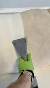 A sofa cushion being professionally cleaned with an upholstery tool by Pronto And Carpet LLC in Charlotte, NC.