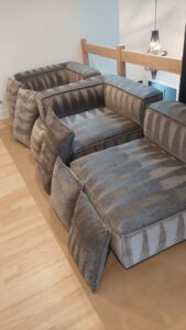 A sofa with cushions removed and stacked, prepared for upholstery cleaning service by Proper Carpet Cleaning in Aurora, IL.