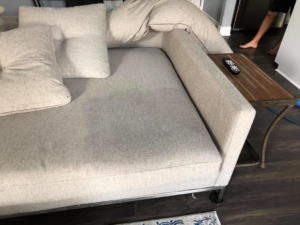 A light-colored sofa with a faint stain on the cushion before cleaning by Erich's Carpet Care in Blue Springs, MO