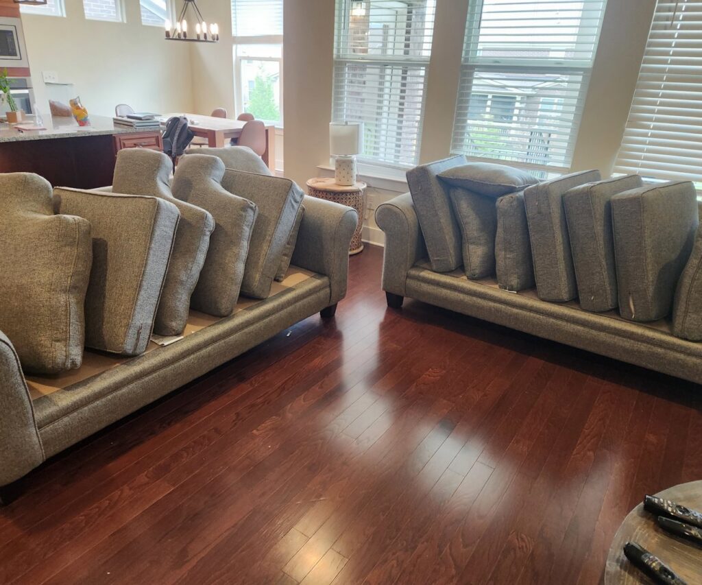 Sofas with cushions stacked and an area rug on a hardwood floor, indicating a cleaning job by Pure Steam Carpet Cleaning in Nashville, TN