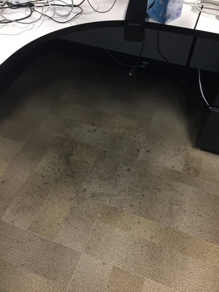 Heavily soiled commercial carpet tiles under an office desk, ready for cleaning by JS Carpet Cleaning in San Jose, CA