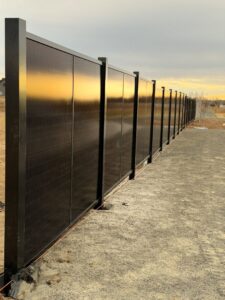 A long solar fence line reflecting the golden light of sunset or sunrise, installed by Sol Fence LLC in Evansville, IN.