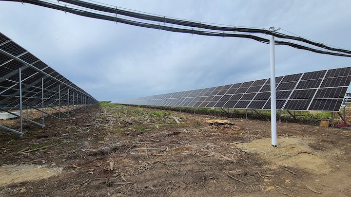 Extensive solar panel array installed in a field, representing renewable energy projects by Premier Electric LLC in Palmer, AK.