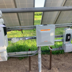 An electrical junction box with a "Photovoltaic Power Source" warning installed under solar panels by Affordable Electric, LLC in Kearney, NE.