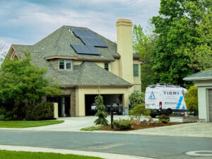 A Tier 1 Electric van parked outside a home with solar panels on the roof, indicating solar service in Boise, ID