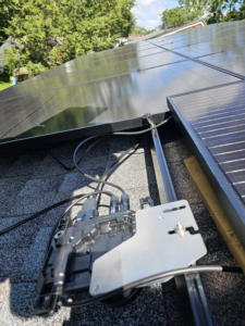 An electrician installing solar panel wiring and an inverter on a roof for Spark Building Energy Solutions in Livonia, MI.