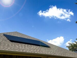 Solar panels installed on a residential roof under a bright blue sky by Premier Power in Edmond, OK.