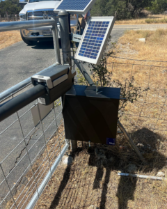 A solar-powered gate opener mechanism installed on a metal gate post by Down South Welding and Fabrication in Canyon Lake, TX.