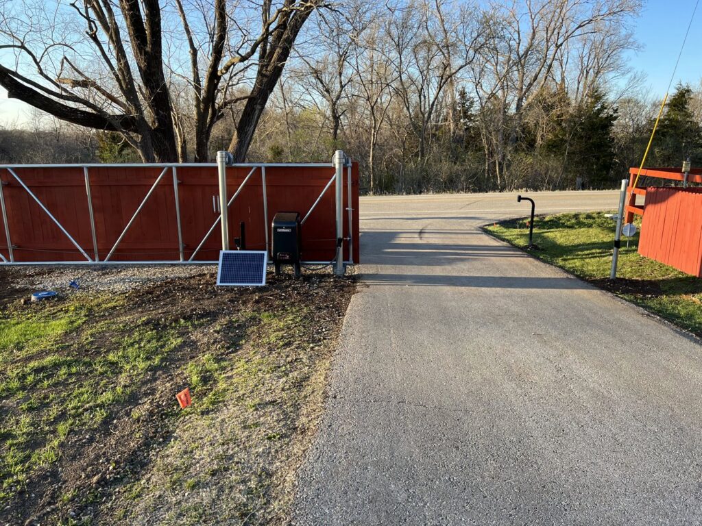 A solar-powered red wooden gate installed by Brothers Gate Operators and Services LLC in Olathe, KS.