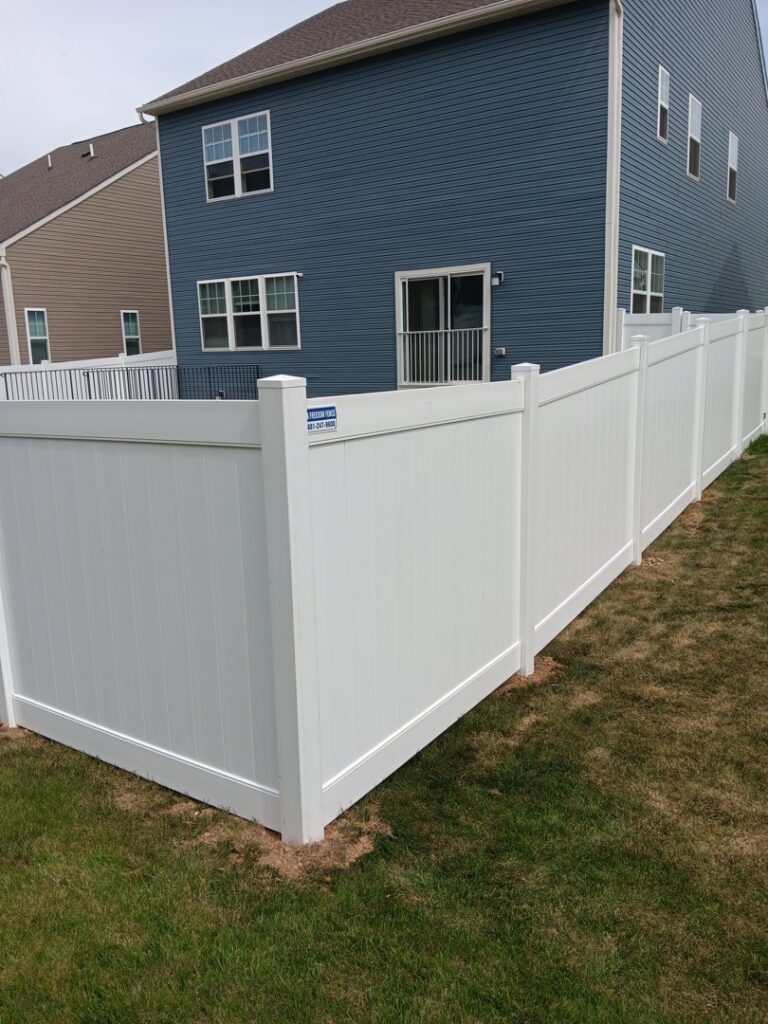 A solid white vinyl privacy fence installed along a property line by A Freedom Fence in Martinsburg, WV.