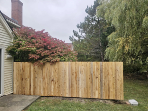 A solid wood privacy fence installed alongside a residential property, offering seclusion by Dirigo Fence Company in Augusta, ME.
