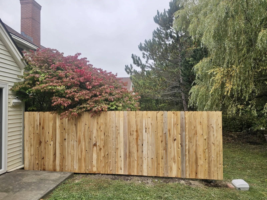 A solid wood privacy fence installed alongside a residential property, offering seclusion by Dirigo Fence Company in Augusta, ME.