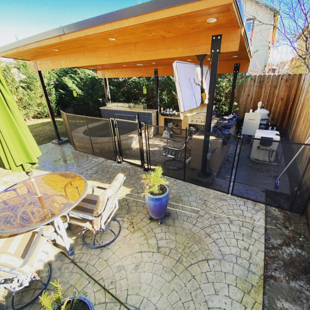 A spa area enclosed by a black mesh safety barrier with a gate, installed by Golden State Baby Barrier in Sacramento, CA.
