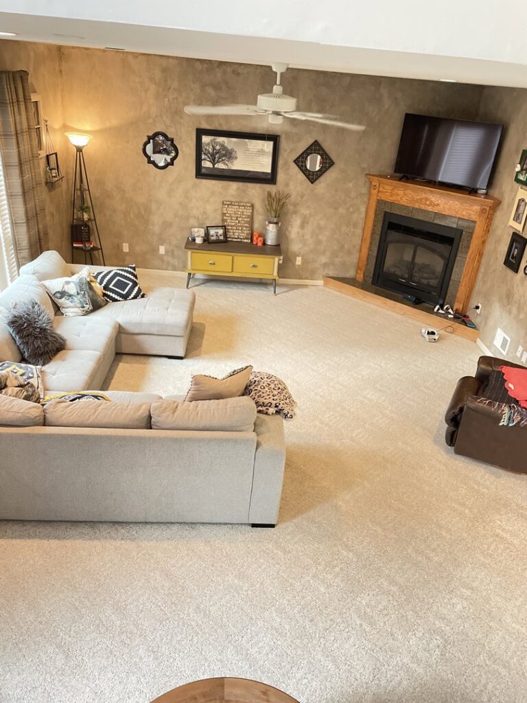 A spacious living room with light-colored wall-to-wall carpet, freshly cleaned by Dewdrop Carpet Cleaning in Kansas City, MO.