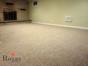 A spacious room with newly installed light-colored carpet and a stone fireplace, completed by Rojas Carpet and Flooring in Denver, CO.