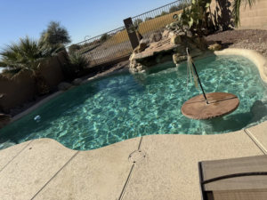 A sparkling clean backyard swimming pool with a rock waterfall feature, maintained by Big Foot Pool Care in Buckeye, AZ