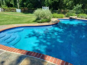 A sparkling clean inground pool with clear blue water and brick coping, maintained by Mid Maryland Pool Service LLC in Frederick, MD.