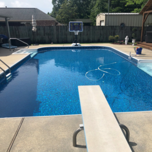 A sparkling clean residential swimming pool with a diving board, maintained by Brocks Pools LLC in Baton Rouge, LA.