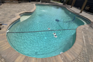 A sparkling blue swimming pool with a robotic pool cleaner in action, maintained by Brigade Pool Services in Tempe, AZ.