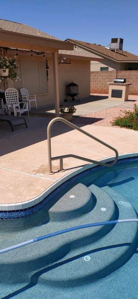 A sparkling clean pool with steps and a handrail, with a pool hose visible, indicating professional service from Space Ranger Pools in Gilbert, AZ.