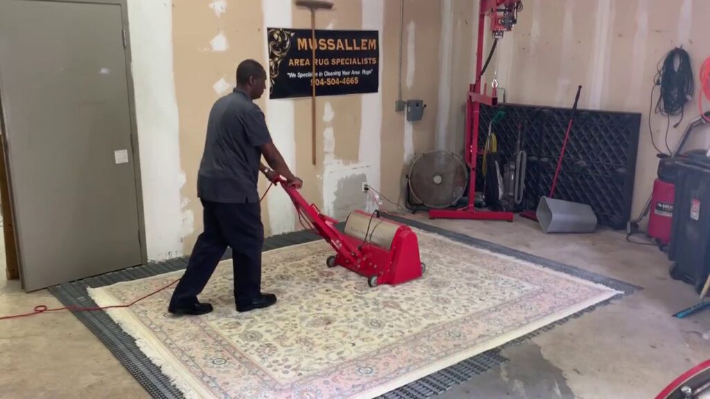 A specialist operating a professional rug cleaning machine on a large area rug at Mussallem Area Rug Specialist in Jacksonville, FL.