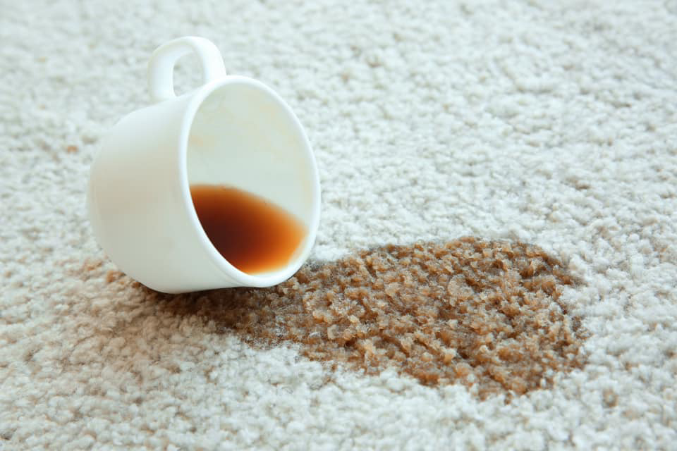 A close-up of a spilled coffee stain on a light-colored carpet, showing a common problem Steamworks Carpet and Upholstery Cleaners in Matthews, NC can fix.