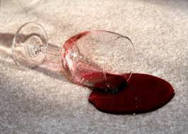 A glass of spilled red wine on a light-colored carpet, a common stain for Lacho's Carpet Cleaning in San Antonio, TX