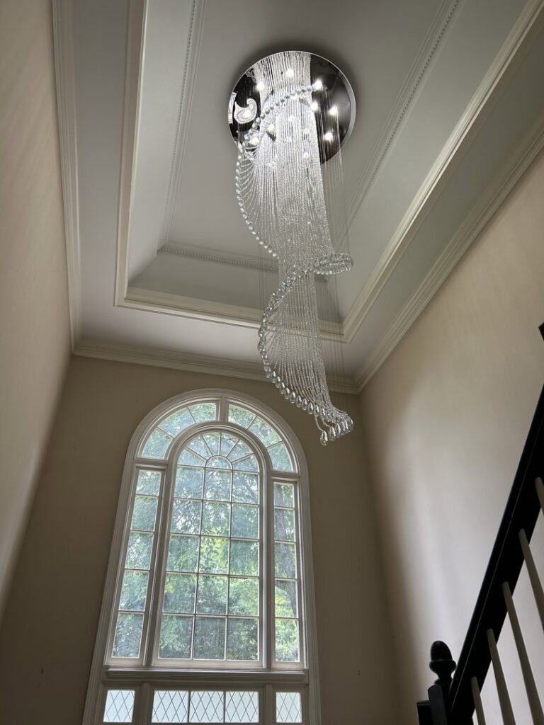 Elegant spiral crystal chandelier installed in a high-ceiling entryway by Perfection Lighting, Design, and Installations in Atlanta, GA.