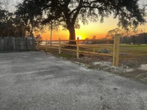 A newly installed split rail fence with a scenic sunset view by Deep South Services LLC in Biloxi, MS.