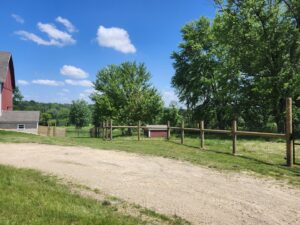 A completed split rail fence with wire mesh installed along a property line by H&S Fencing & Supply in Linden, WI.